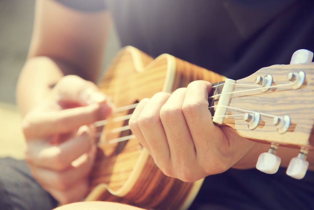 Person Playing Brown Ukulele